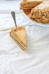 round napoleon cake, with caramel cream and a cut off piece, on a white background. copy space