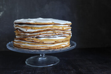a whole round honey cake on a stand against a dark background - 536442684