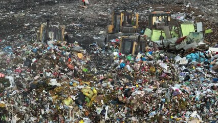 Dozer on landfill. Garbage dump with waste plastic, rubbish and polyethylene. Solid waste disposal and landfill. Landfill with solid household garbage. Environmental pollution. Waste toxic mountain. 