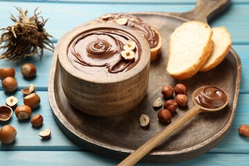 Bowl of tasty chocolate paste with hazelnuts on light blue wooden table