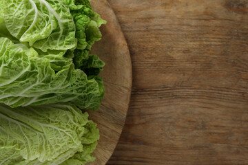 Fresh ripe leaves of Chinese cabbage on wooden table, top view. Space for text