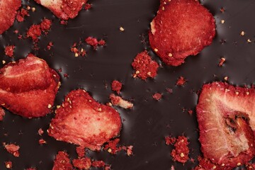 Chocolate bar with freeze dried strawberries as background, closeup