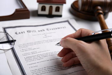 Woman signing last will and testament at white table, closeup - obrazy, fototapety, plakaty