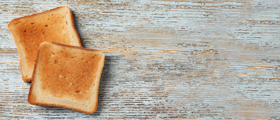 Slices of delicious toasted bread on wooden table, top view with space for text. Banner design