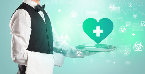 Obraz premium Handsome young waiter in tuxedo holding healthcare icons on tray