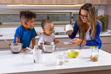 Mother playing and sharing food preparation with her son and friend