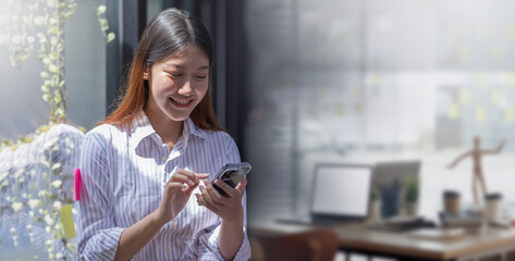 Portrait of happy Young Asian business woman using mobile phone indoor, Asian businesswoman working in modern office.