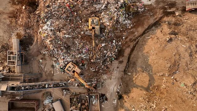Landfill with Construction waste (CDW). Trash disposal for recycling and re-use. Excavator log grab crane on landfill. Recycling of Construction waste or debris. Secondary raw. Wood Waste Recycling.
