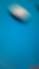 Abstract blurred background with the dominant blue color, at the top there is a white object.