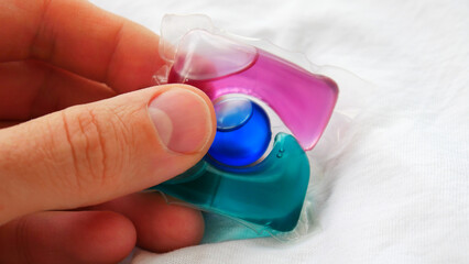 Close-up of a male hand holding a colorful washing capsule