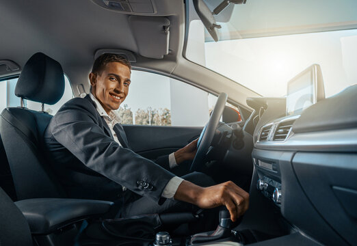 Young male businessman in a car rental service. Test drive concept. Blurred background