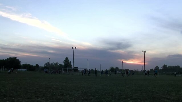 Group of High School Students playing Soccer at Sunset. 