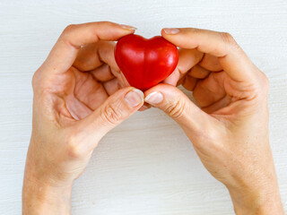 health, medicine and love, relationship, charity, donate, kind, world heart day concept - close up of female hands with small red heart on white background