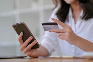 Close up. woman holding smartphone and using credit card for online shopping.