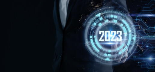 Smart businessman pointing digital dashboard in 2023 on dark blue background. Futuristic technology...