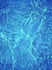 Defocus blurred transparent blue colored clear calm water surface texture with splashes and bubbles. Trendy abstract nature background. Water waves in sunlight with copy space. Blue watercolor shining