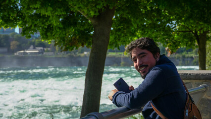 Joven adulto hispano posando cerca de un rio en un dia soleado. Parque natural de Niagara Falls 