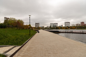The road in the city park along the autumn pond