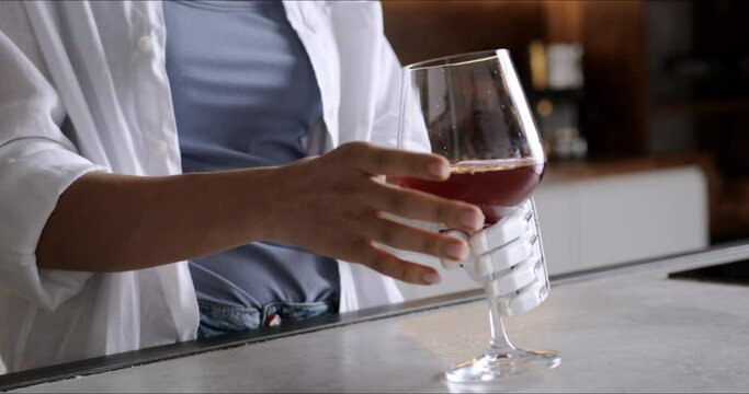 Happy girl with prosthetic arm holds glass of wine in artificial prosthetic limb hand at home