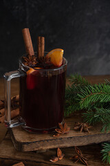 Mulled wine, a hot warming drink with spices, cinnamon, orange and anise on a wooden background.