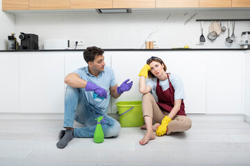 Tired couple sitting on the floor after exhausted cleaning day at home