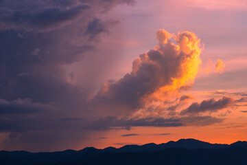Cumulonimbus cloud and rain fall over the mountain during sunset sky with golden light