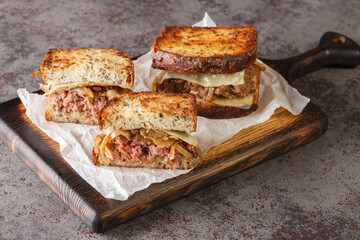 patty melt is a sandwich consisting of a ground beef patty with melted cheese and topped with caramelized onions between two slices of griddled bread closeup on the wooden board on the table