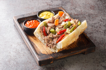 Delicious Chicago Italian beef sandwich with slow cooked beef and Giardanarra close-up on a wooden tray on the table. horizontal