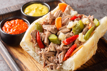 Homemade Chicago Italian Beef Sandwich with Giardanarra closeup on the wooden tray on the table. Horizontal
