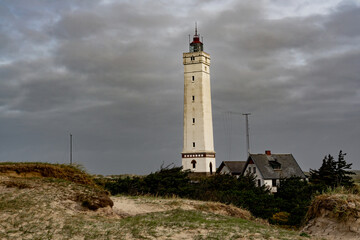 Fototapeta na wymiar Blåvandshuk Lighthouse at the westernmost point on Denmark under a dramatic autumn sky