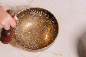 Close-up of a woman's hand playing on a Tibetan bowl filled with water
