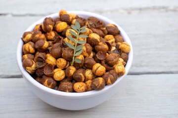 Roasted Chickpea  or Garbanzo Bean Coated with Spices, Salt and Chili Powder in a Bowl Isolated White Wooden Background, Also Known as Bengal Gram or Egyptian Pea