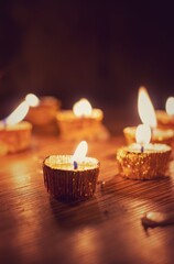 Candle with Glowing Flame Lit on Diwali Night with Selective Focus Isolated on Wooden Table with Candlelight Background, Deepavali or Happy Diwali Festival Celebration Conceptual