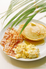 A stack of delicious pancakes with bacon, honey, nuts and caramelized banana. A hearty breakfast.