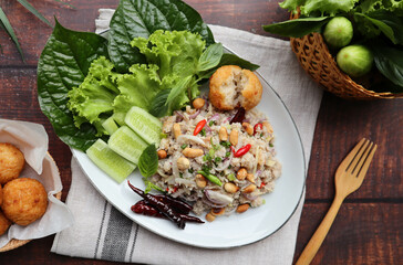 Yam Naem Khao Tod:  Thai fermented Spicy pork Salad with Crispy Rice ball at top view with vegetables on the side - Flat lay Thai appetizer food