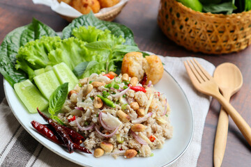 Yam Naem Khao Tod:  Thai fermented Spicy pork Salad with Crispy Rice ball at top view with vegetables on the side - Flat lay Thai appetizer food