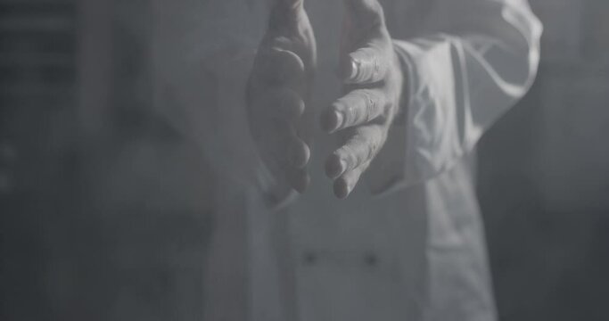 Baker clapping his hands covered with flour. Baker working with dough and flour. Professional cook claps hands and powder fly. Baking concept.