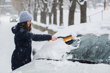 Woman removing snow from car windshield