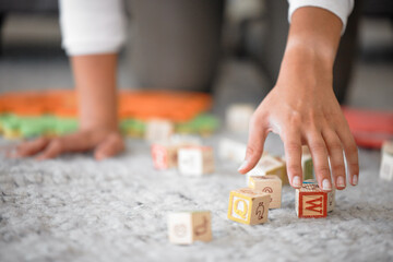 Hands, cleaning and toys with a woman or mother picking up building blocks in the house to clean or...