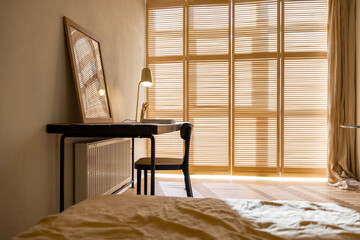 Cozy worplace with wooden table, chair and window blinds on background in bright apartment studio