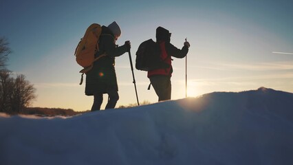 nordic walking in winter. winter hike group of tourists silhouette. teamwork travel. two hikers...