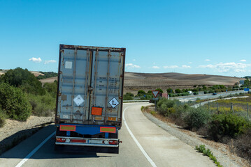 Truck circulating with a container marked with an orange panel, transport under ADR, with danger...