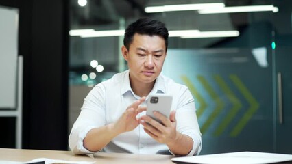 angry annoyed displeased asian business man in office using smart mobile phone failure Cannot enter data no weak internet network Male user frustrated by bad news signal service fail on smartphone app - Powered by Adobe