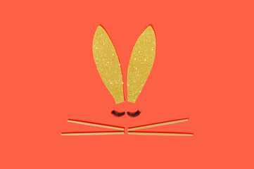 Golden rabbit ears with eyelashes and Chinese chopsticks on a red background. Chinse New Year and Easter concept.