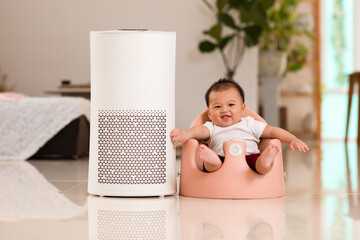 Air purifier and baby smile in cozy white bedroom for filter and cleaning removing dust PM2.5 HEPA...