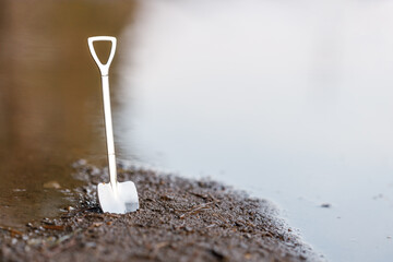 a shovel is stuck into the soil on the shore of a reservoir