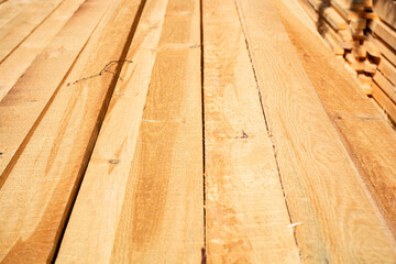Stacked wooden planks with natural patterns for construction and design. Rough wooden planks lying in rows, close-up.