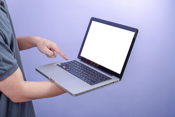 Man holding laptop with blank screen on purple background.