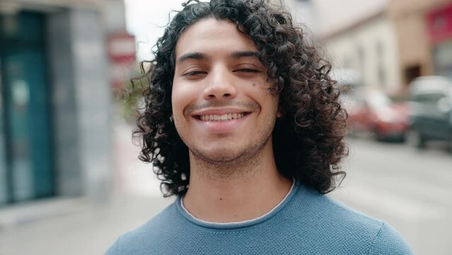Young latin man smiling confident standing at street