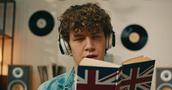A curious man listens to a new audiobook using wireless headphones. Learning new phrases in English. Learning by listening. Studies. A young man is learning new vocabulary.